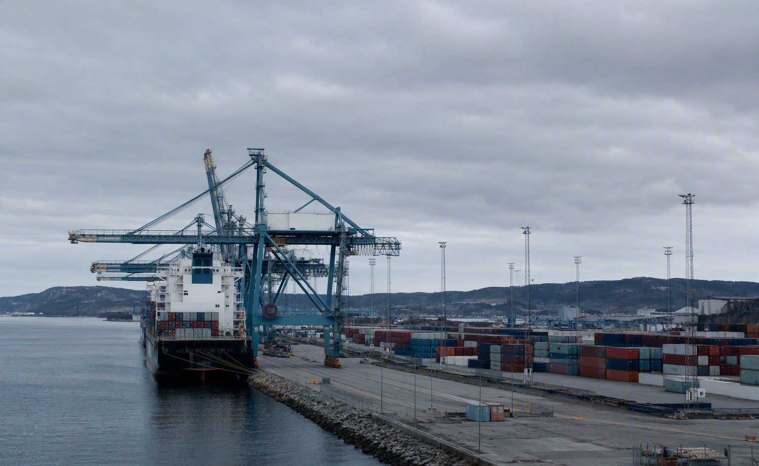 Illustrative image — Container port with cranes and stacked shipping containers under an overcast northern European sky, representing food ingredient imports into the United Kingdom